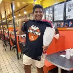 Proud winner wearing the official black Man v. Food Ultimate Challenge finisher T-shirt at Chick and Ruth's Delly.